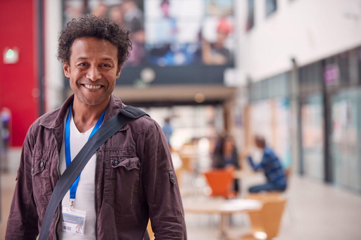Economics student smiling in a modern university hallway with study spaces. Learning and higher education concept.