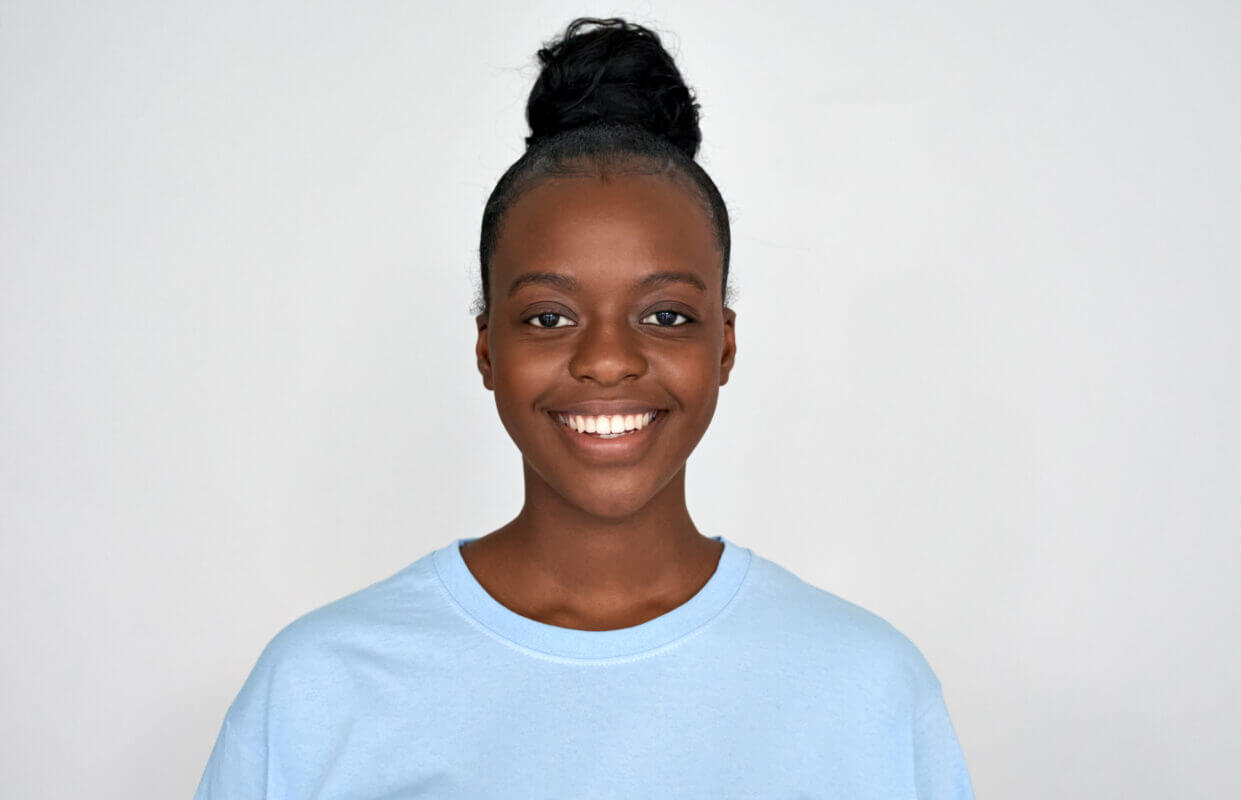 Smiling young Black woman, economics student portrait. Happy, confident, wearing a blue shirt. Stock photo.