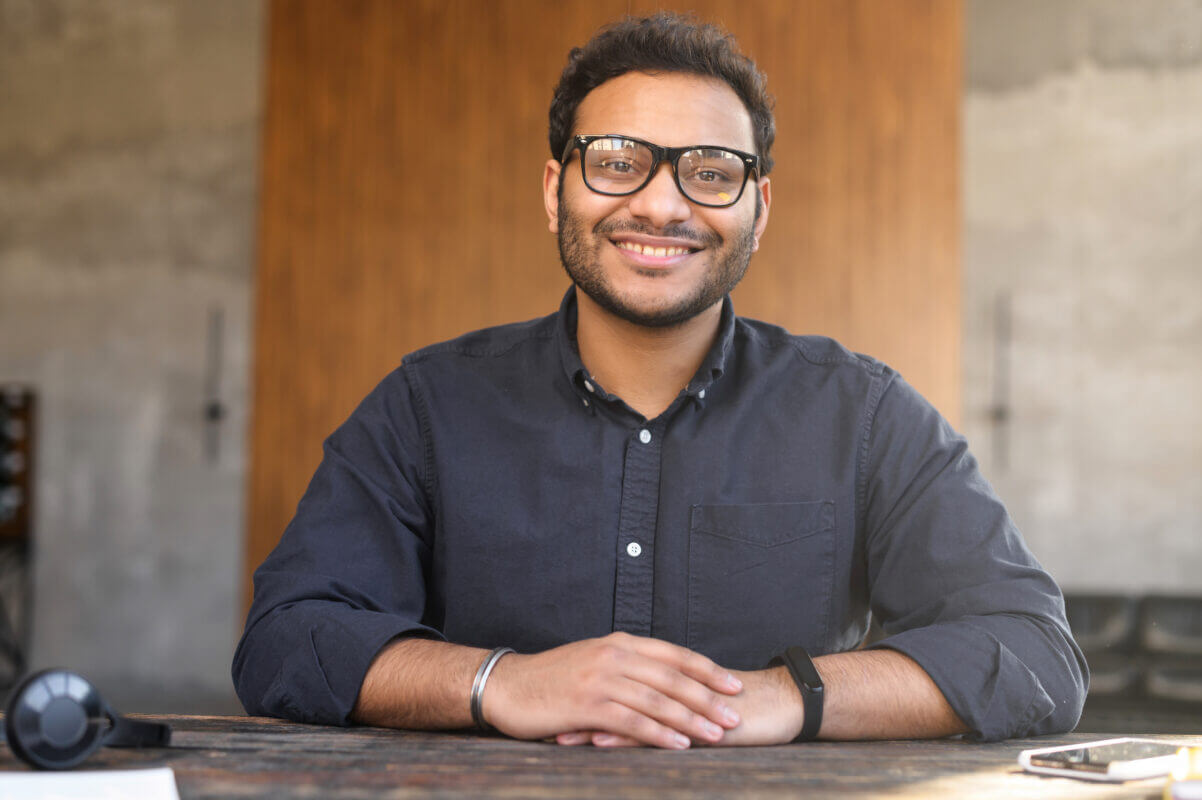 Economics student portrait. Smiling man with glasses at desk. Education and learning concept.