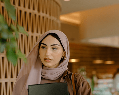 Physics student with hijab holding tablet, studying science and technology in modern learning environment.